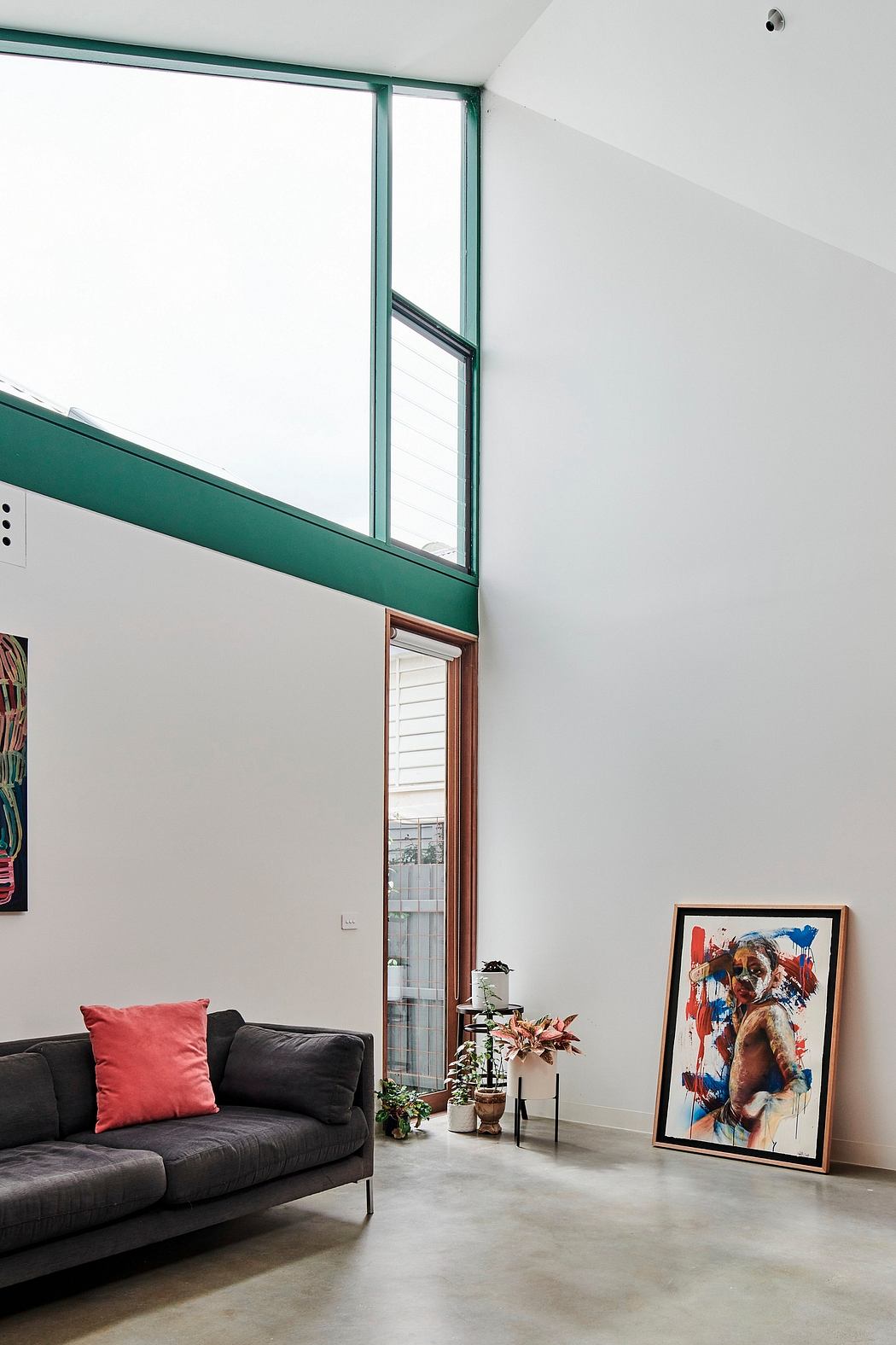 Modern living room with high ceilings, large windows, and abstract artwork.