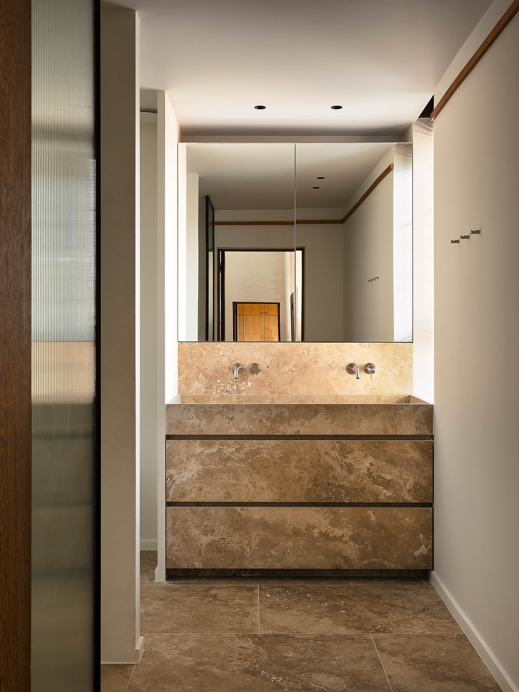 Modern bathroom with sleek marble vanity, recessed lighting, and large mirror.