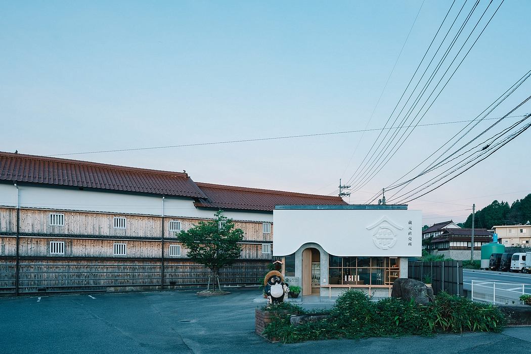 Traditional Japanese-style buildings with tiled roofs, surrounded by lush greenery and power lines.