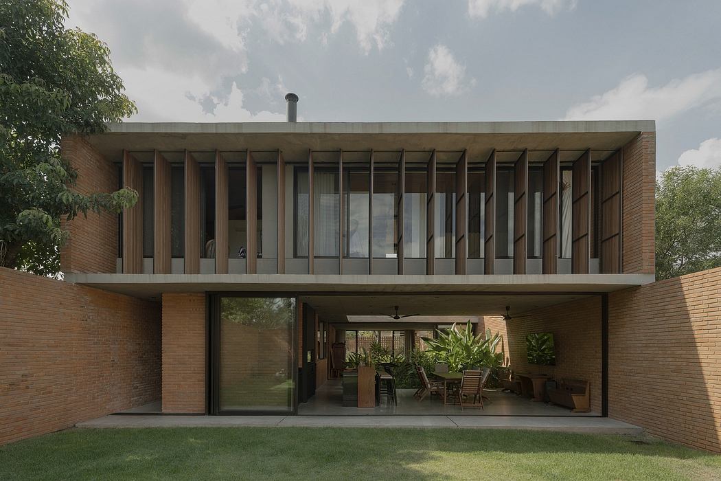 Modernist brick residence with expansive glass walls and shaded outdoor seating area.