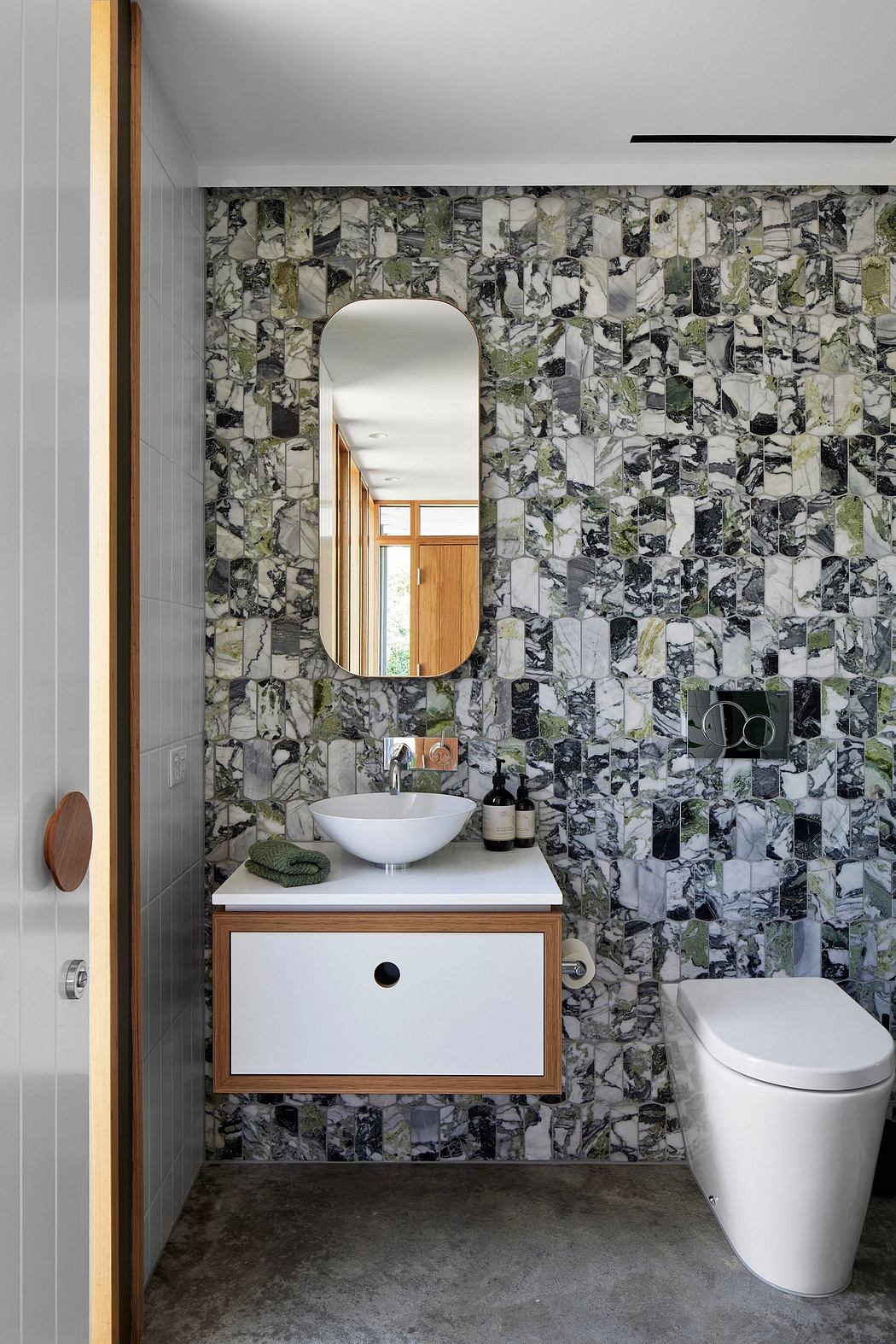 Modern bathroom with patterned wall tile, floating vanity, and arched mirror.