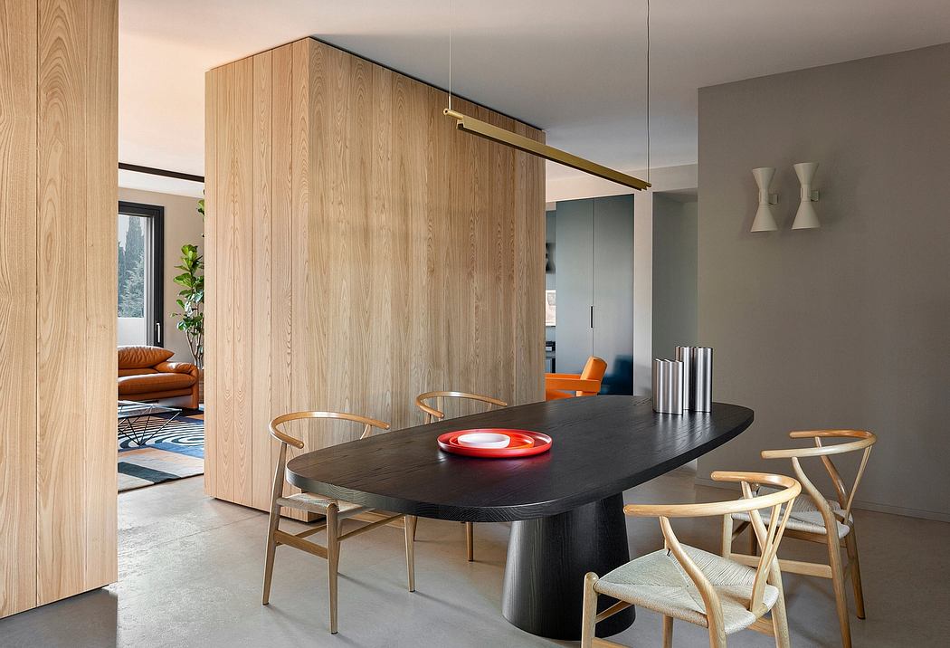 A modern dining area with a large oval table, wooden chairs, and warm-toned wood paneling.