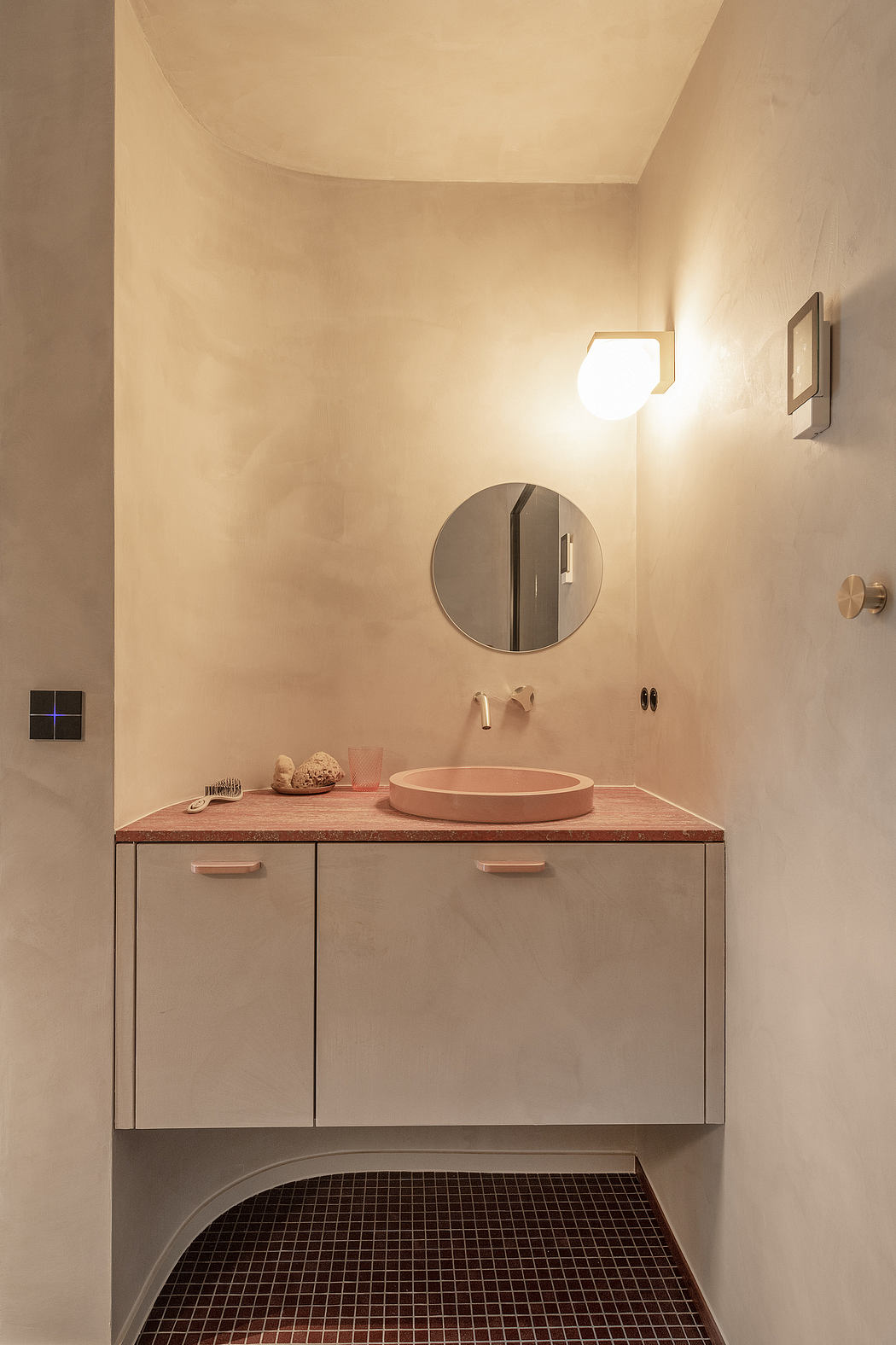 Warm-toned, minimalist bathroom with round mirror, vessel sink, and wood-topped vanity.