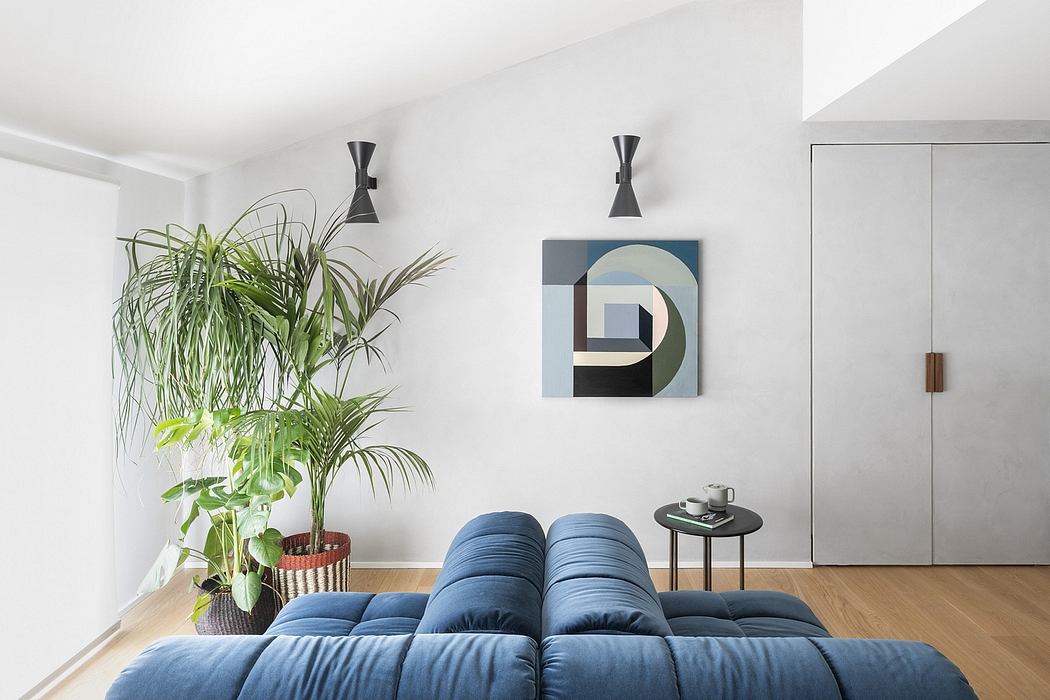 A minimalist living room with a large blue couch, modern wall art, and potted plants.