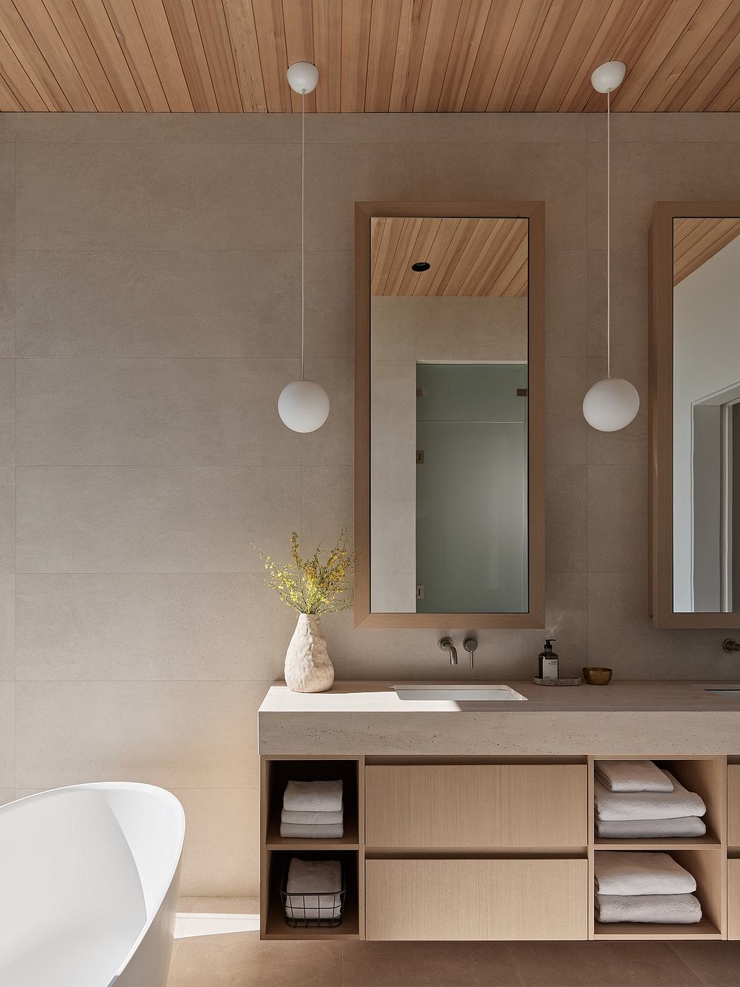 A modern bathroom with a wooden ceiling, concrete walls, and a minimalist vanity with ample storage.
