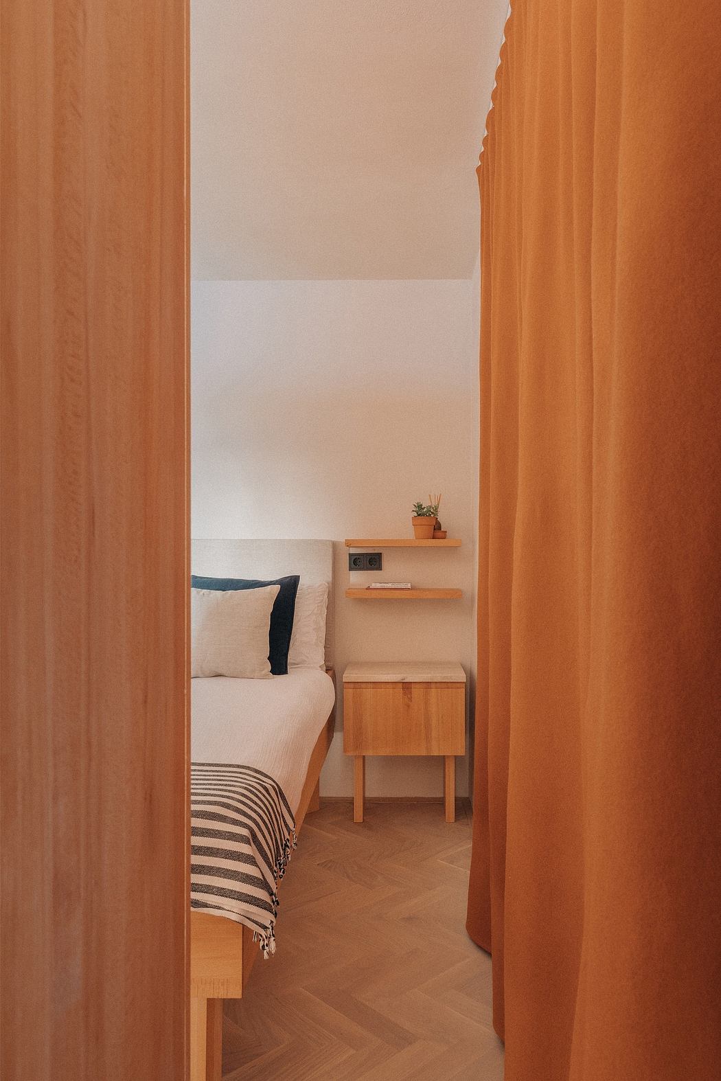 Cozy bedroom with warm wooden furnishings, shelving, and soft curtains creating a welcoming atmosphere.