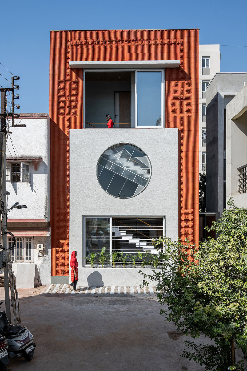 A vibrant red-accented building with a circular window and geometric patterned facade.