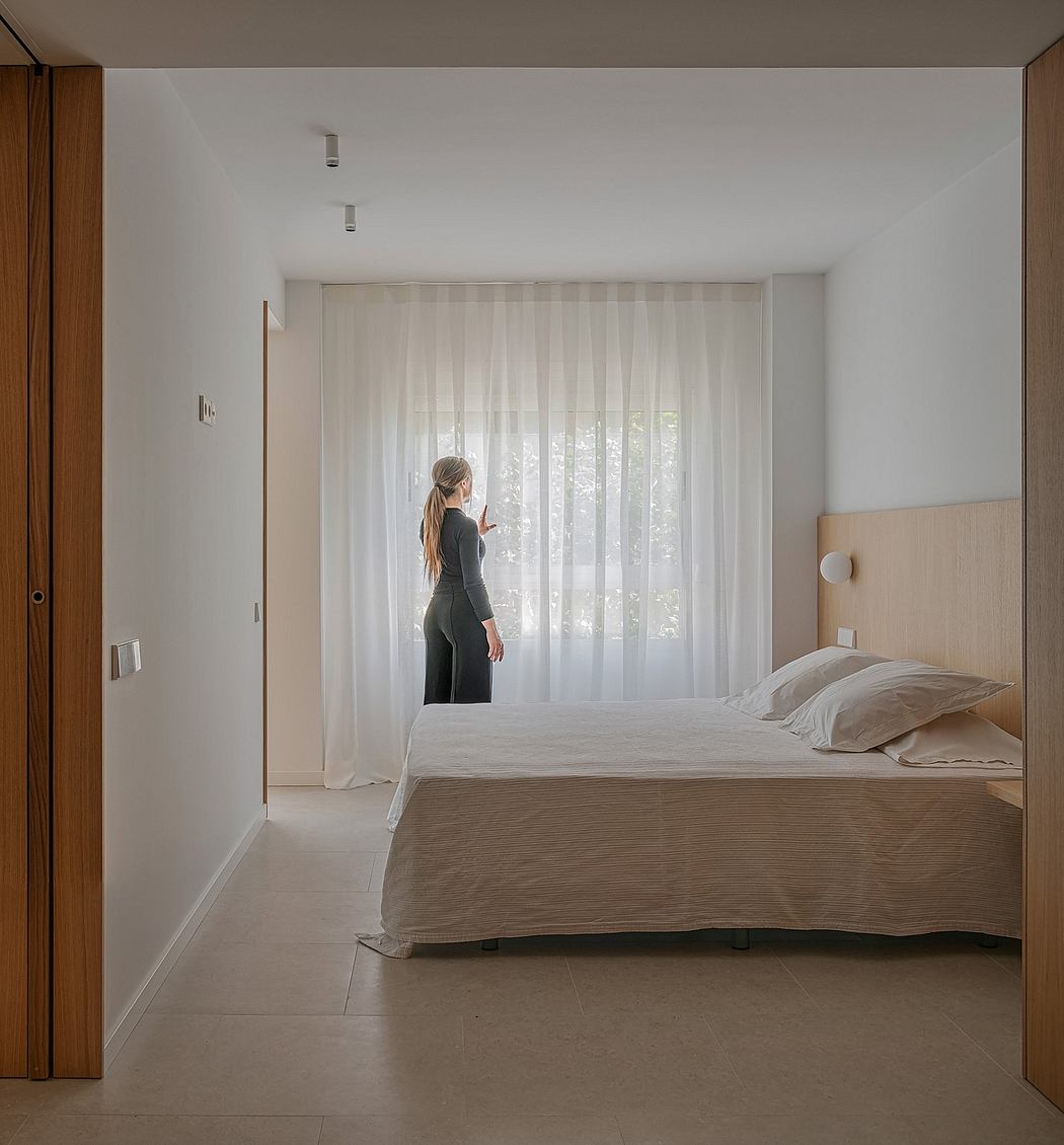Minimalist bedroom with floor-to-ceiling curtains, bed, and neutral color scheme.