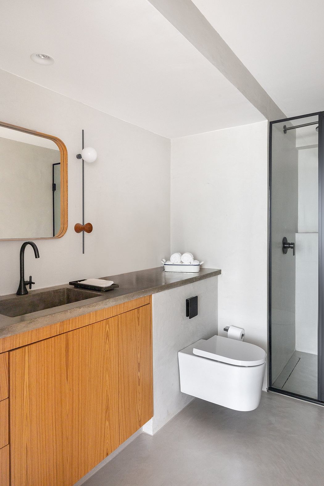 Minimalist bathroom design with wooden vanity, concrete countertop, and modern fixtures.