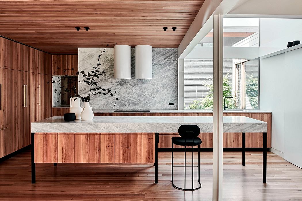 A sleek and modern kitchen with wood paneling, marble countertops, and minimalist furnishings.