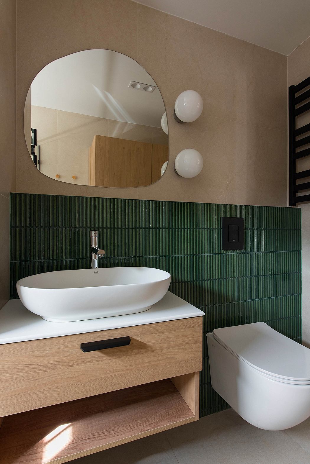 A modern bathroom with a large circular mirror, white vanity, and green tiled wall.