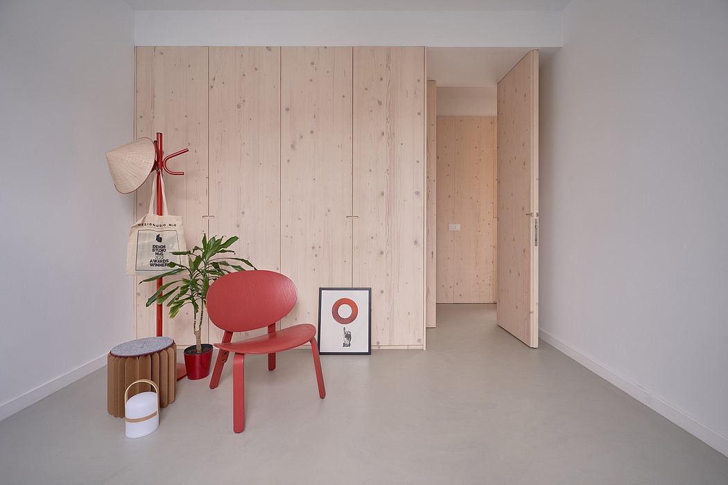 Clean, minimalist interior with wooden panels, red chair, and potted plant.