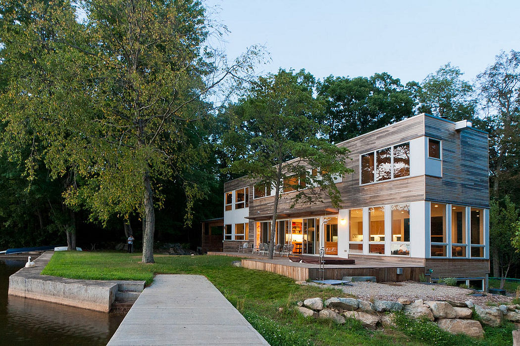 Sleek, contemporary lakeside home with wooden siding, glass walls, and deck overlooking water.
