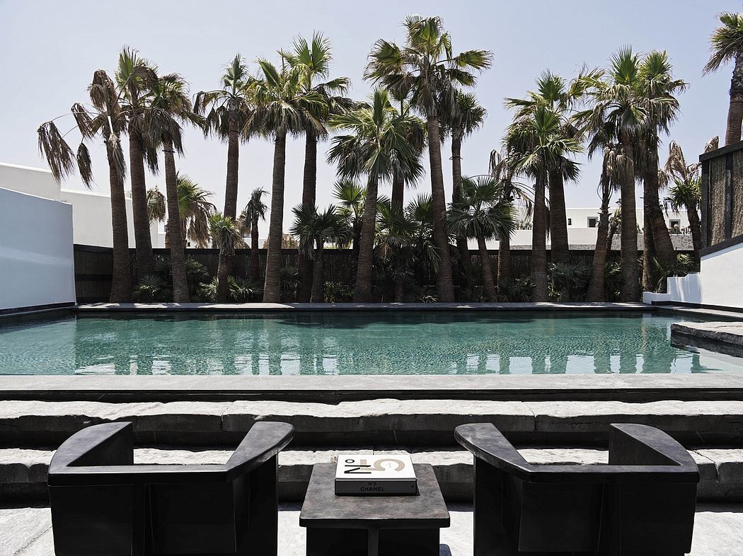 Serene poolside scene with towering palm trees, sleek black loungers, and a Chanel-branded table.