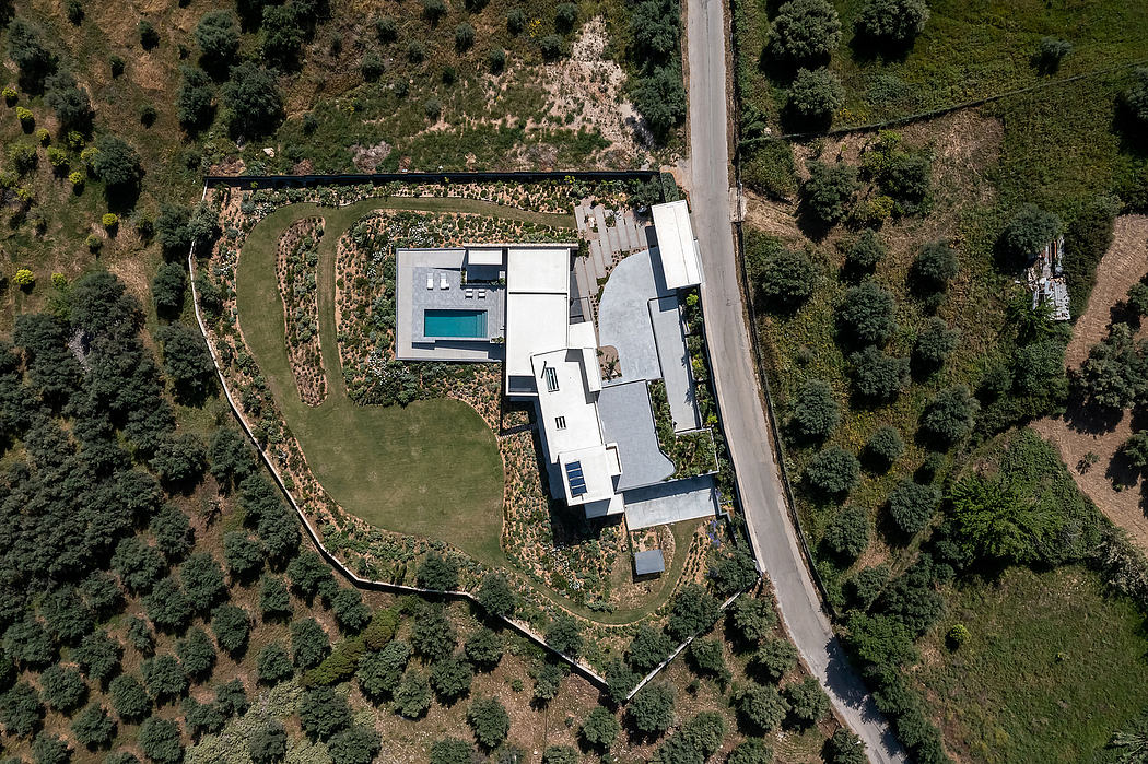 Aerial view of a modern, angular residential building with a swimming pool nestled in lush greenery.