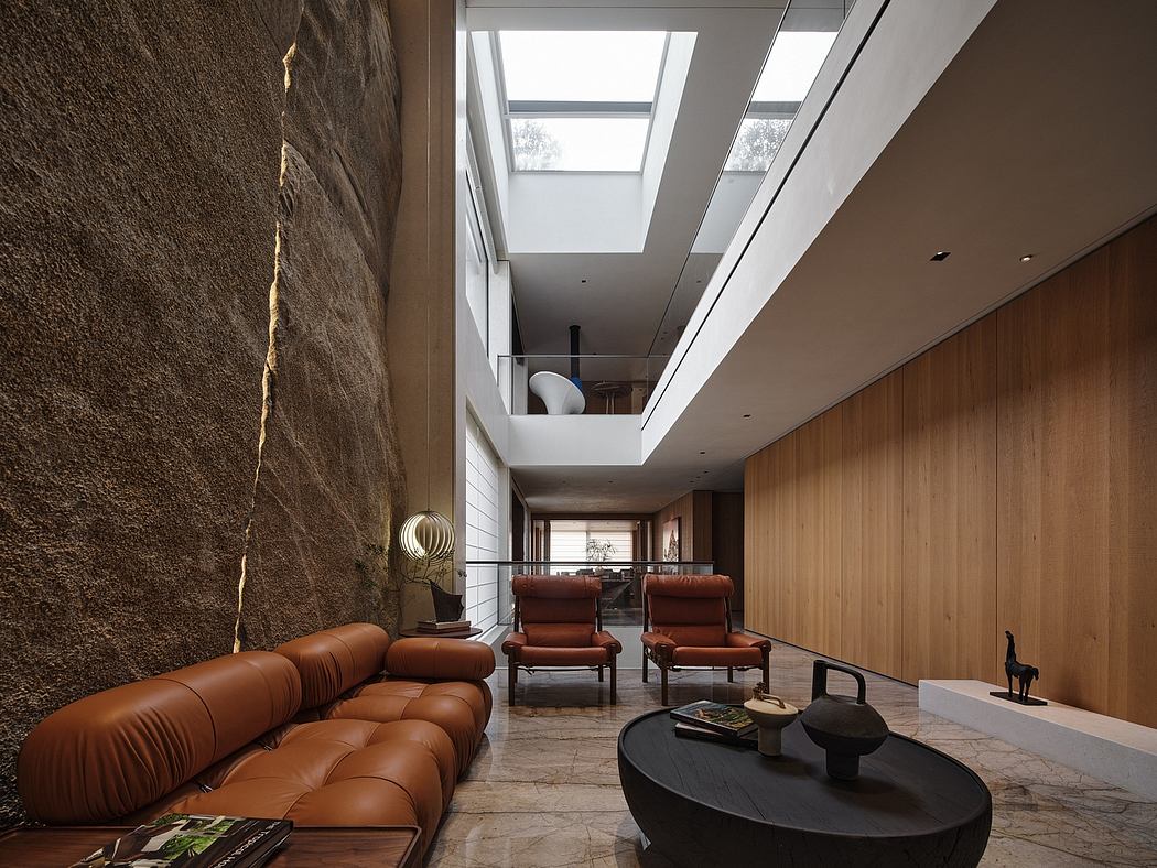 Spacious modern interior with exposed stone wall, skylights, wood paneling, and leather seating.