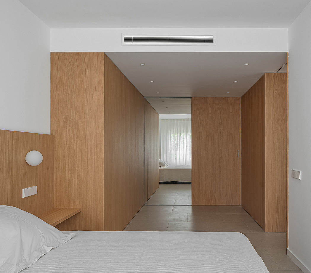 Modern bedroom interior with minimalist wooden paneling and recessed lighting.