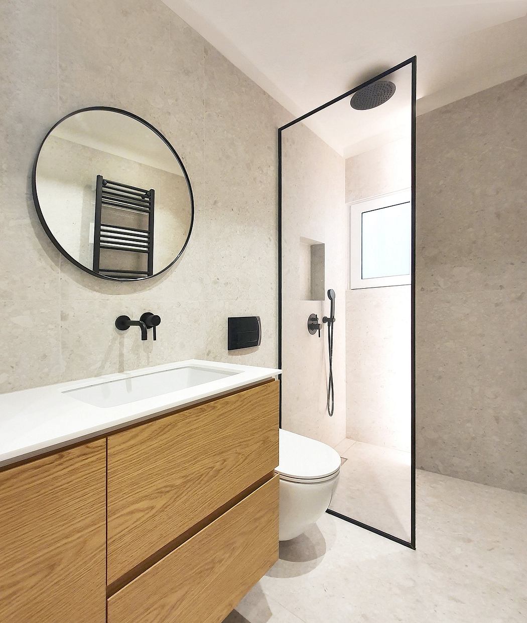 Minimalist bathroom with circular mirror, wooden vanity, and black frame shower.