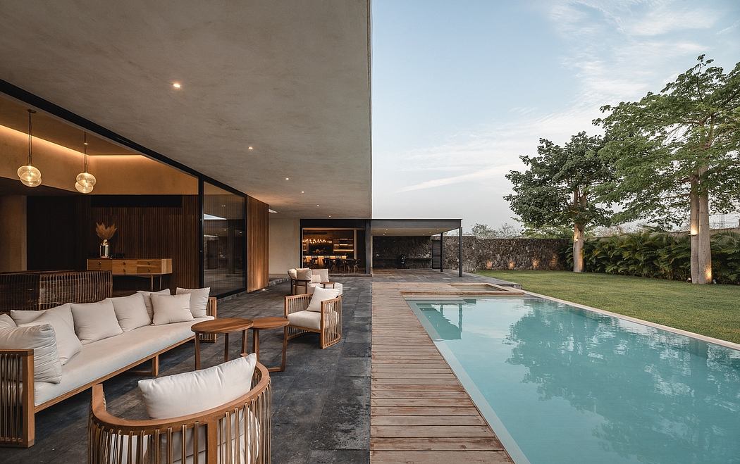 Expansive outdoor lounge area with pool, surrounded by lush greenery and modern architecture.