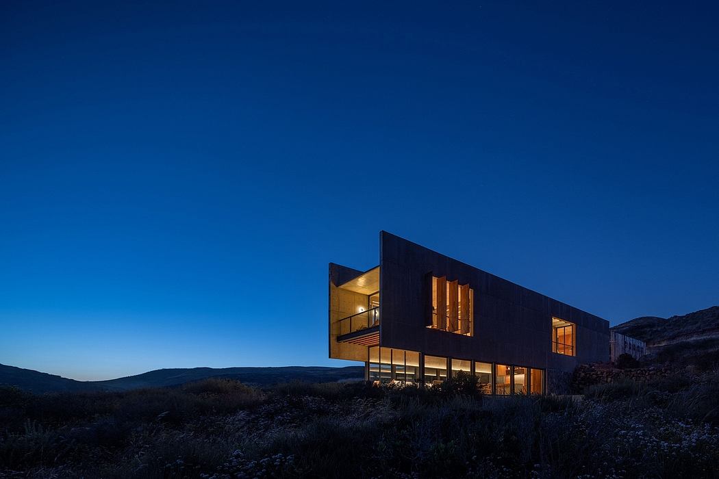 Modern architectural structure with large windows and striking black exterior against the night sky.