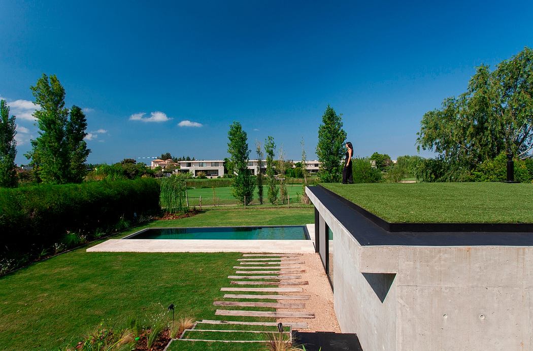 Sleek, modern architecture with a minimalist concrete pool house and lush, well-manicured landscape.
