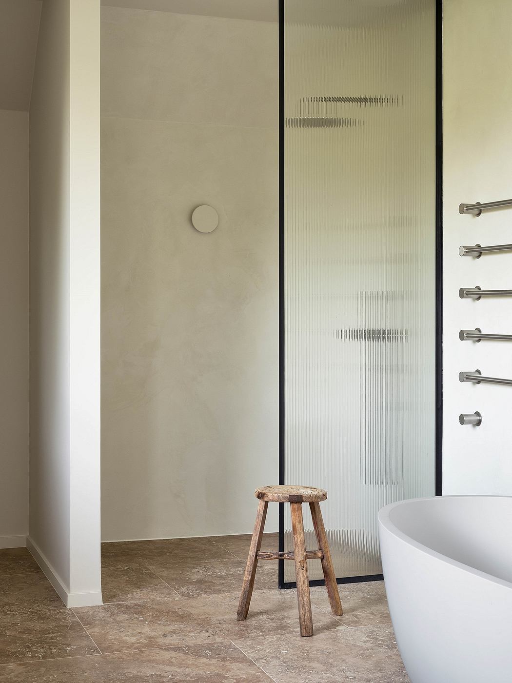 Minimalist bathroom interior with textured walls, wooden stool, and clean lines.