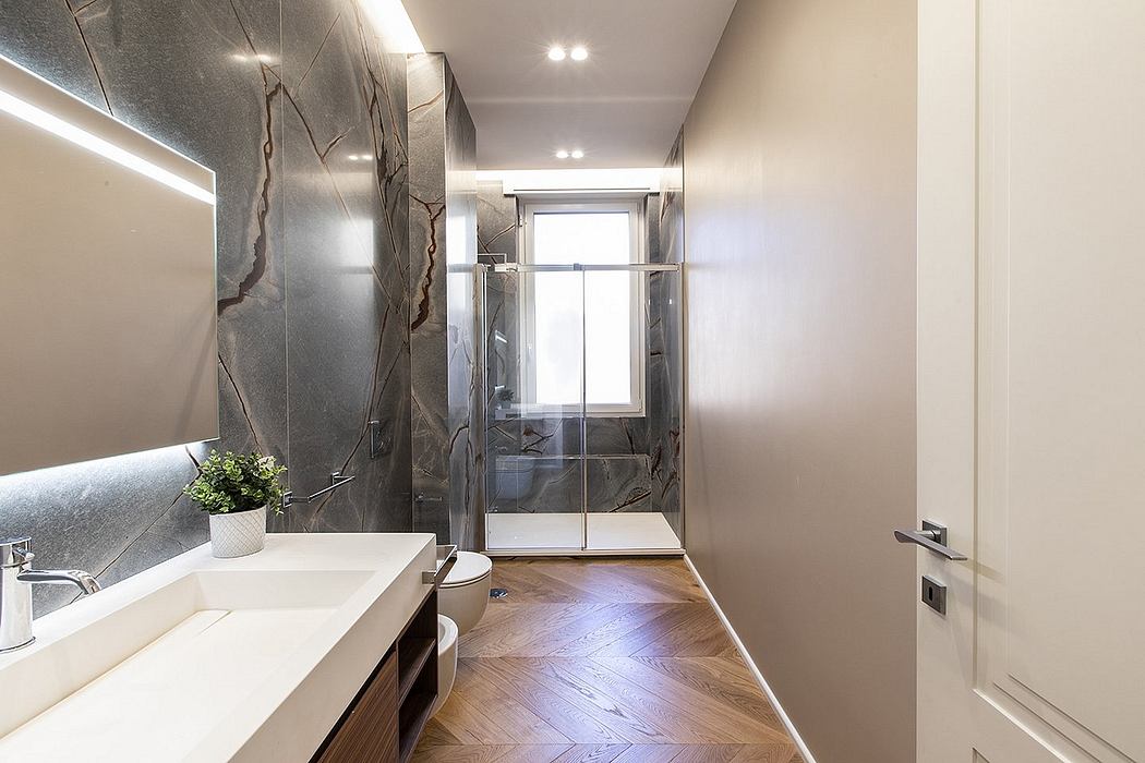 Chic, modern bathroom with sleek marble walls, vanity, and hardwood floor pattern.
