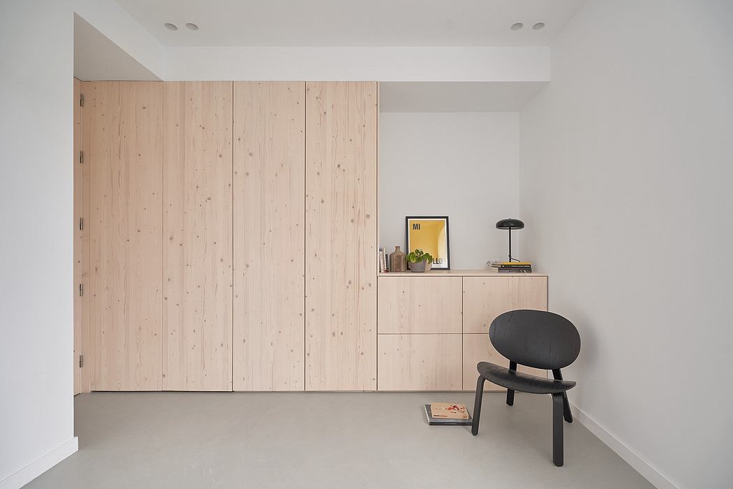 Minimalist room design with wooden cabinetry, decorative shelving, and simple chair.