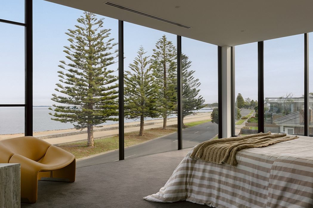 This modern bedroom offers sweeping views of the coastline through floor-to-ceiling windows.