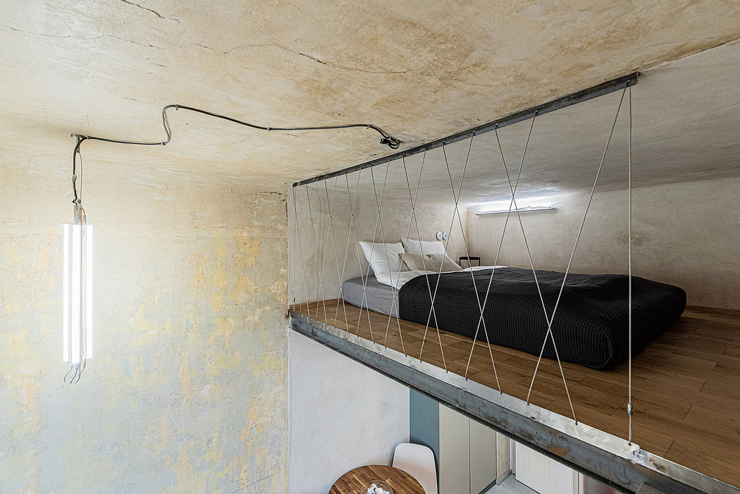 Rustic bedroom interior with suspended metal bed frame and wooden plank floor.