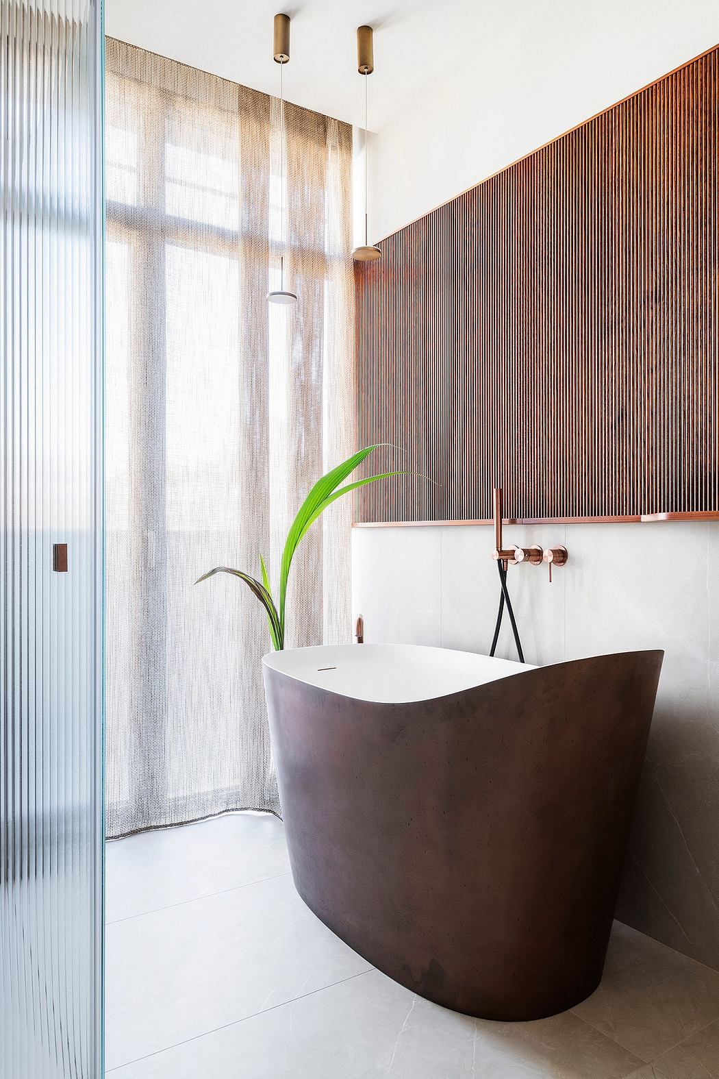 A sleek, modern bathroom with a freestanding tub, wood paneling, and pendant lighting.