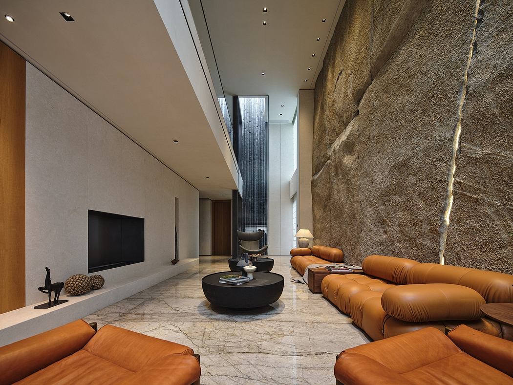 Spacious modern living room with natural stone walls, leather sofas, and minimalist decor.
