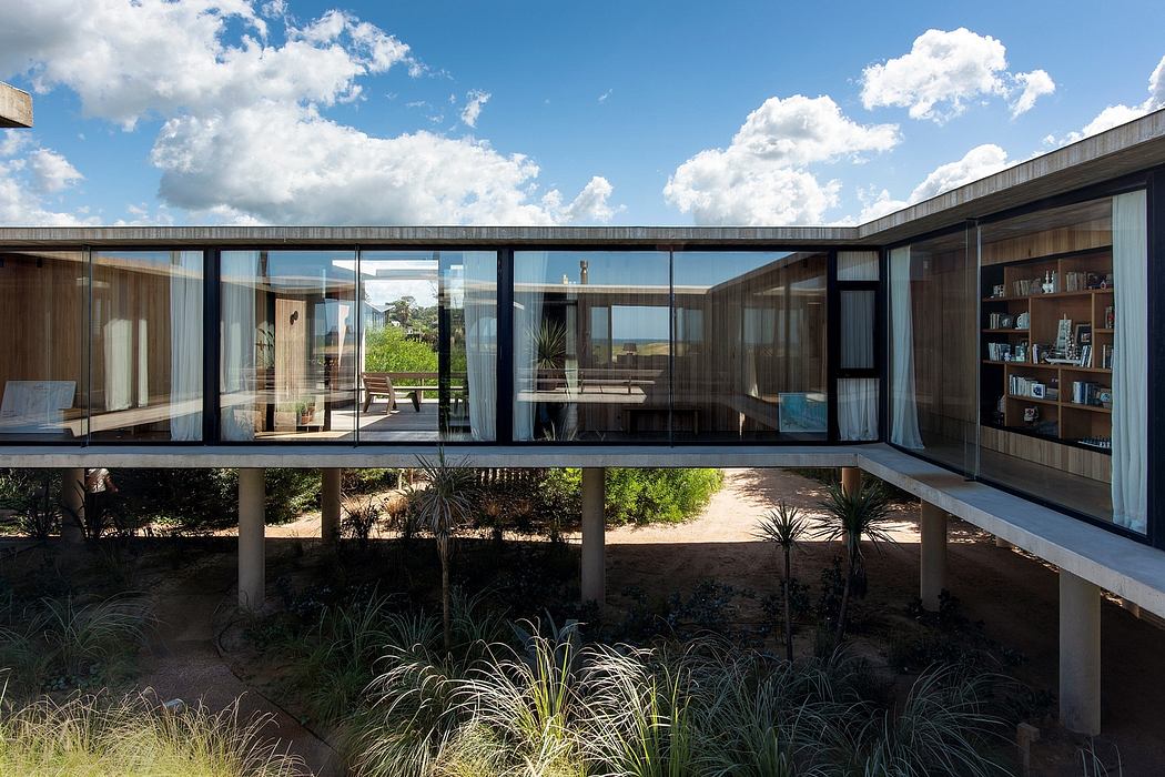 A modern, glass-enclosed structure on stilts, surrounded by lush vegetation.