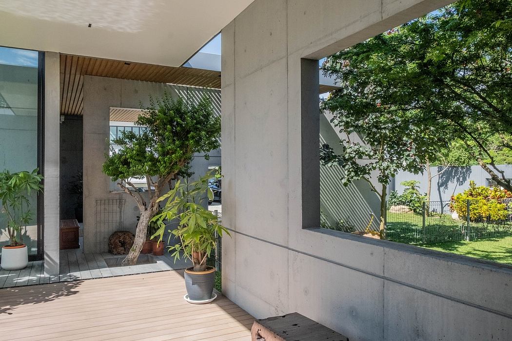 A modern, minimalist concrete exterior with large windows and lush, green foliage.