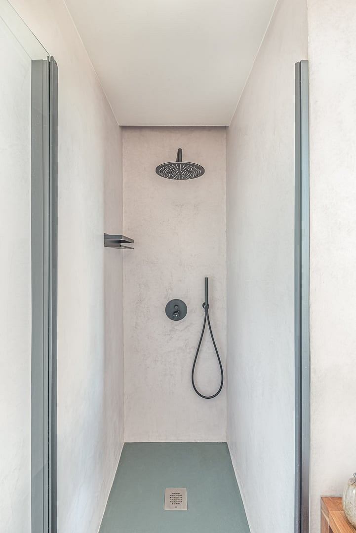 A minimalist bathroom with a sleek, modern shower design and neutral tile flooring.