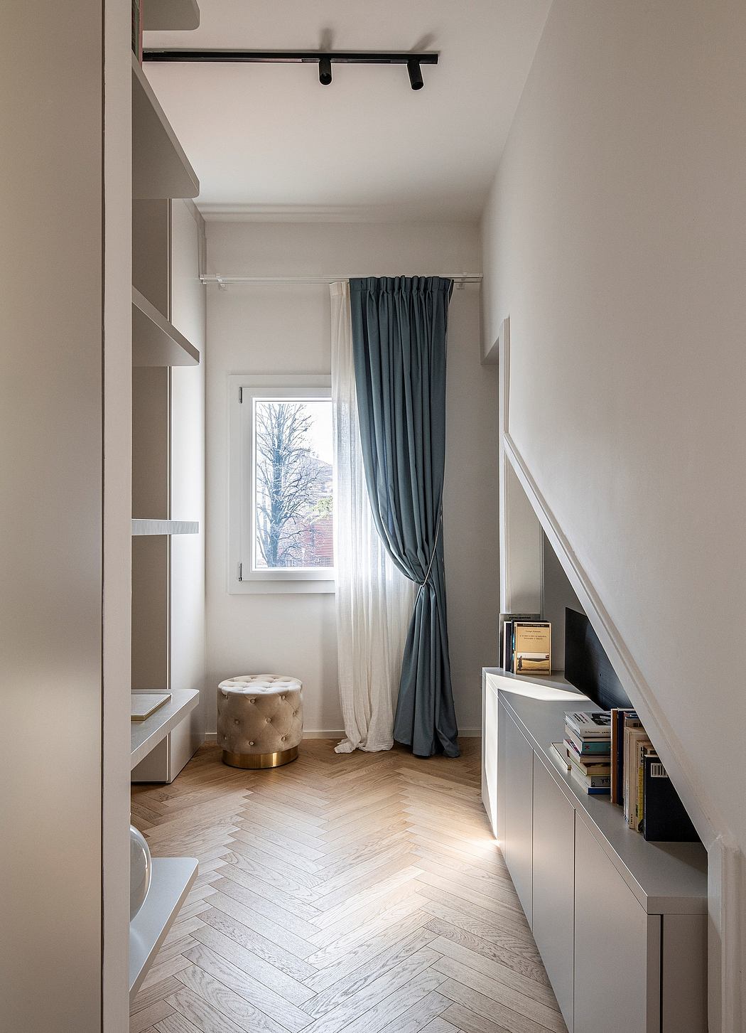 Elegant minimalist room with herringbone flooring, built-in shelving, and delicate curtains.