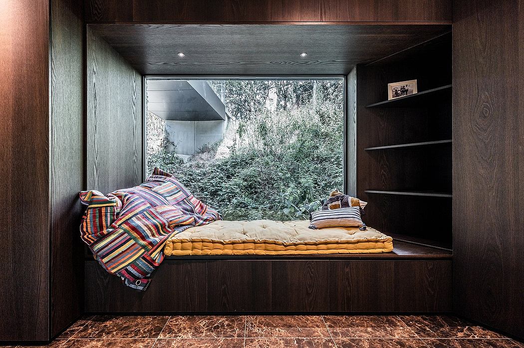 Cozy window nook with plush bedding, built-in shelving, and picturesque forest view.
