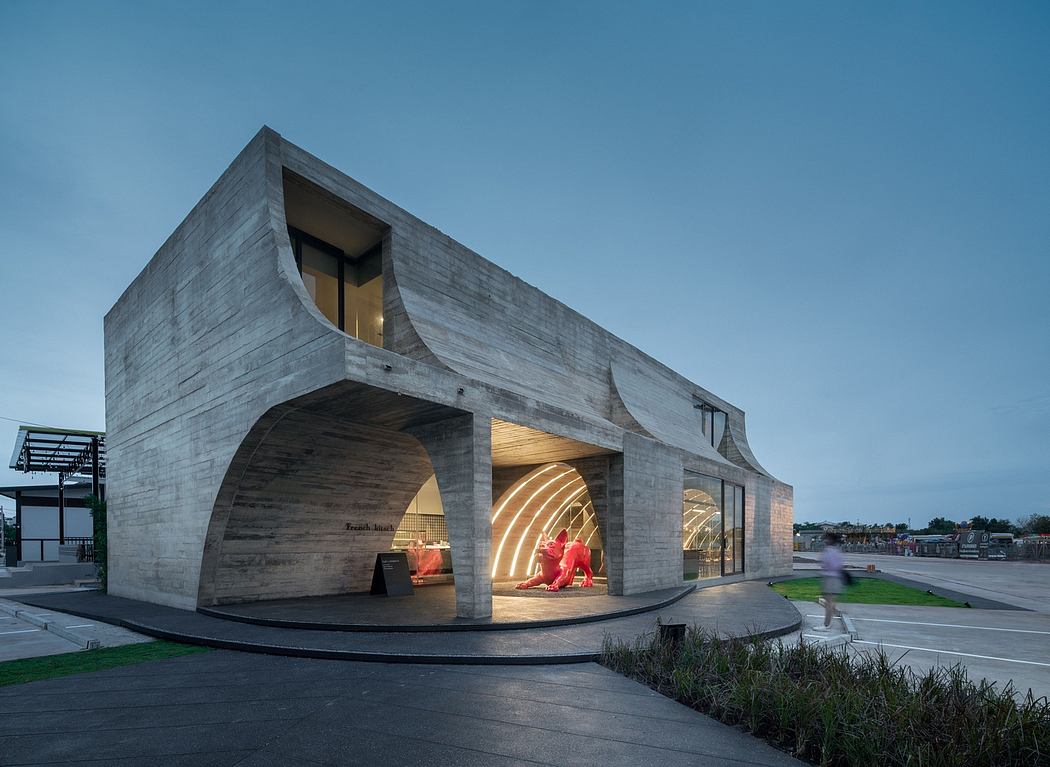 A striking concrete structure with curved arches, illuminated interiors, and landscaped surroundings.