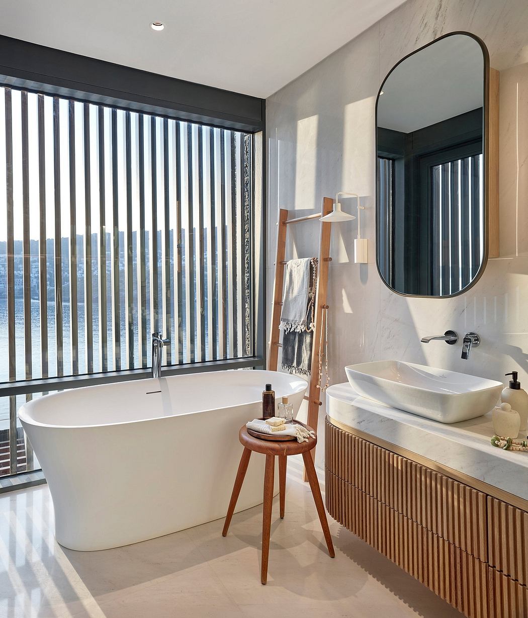 Sleek, modern bathroom with freestanding tub, vanity, and arched window offering scenic views.