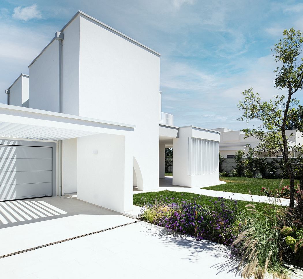 A modern, minimalist home with clean lines, a garage, and lush landscaping.