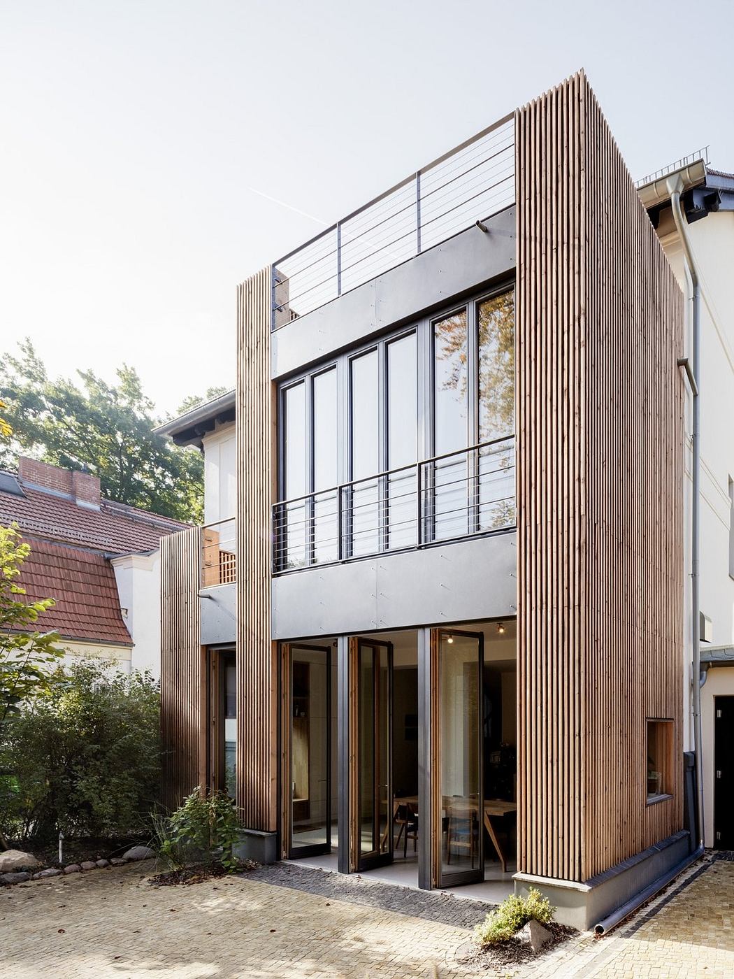 Modern wooden facade with glass doors, balcony, and architectural details.
