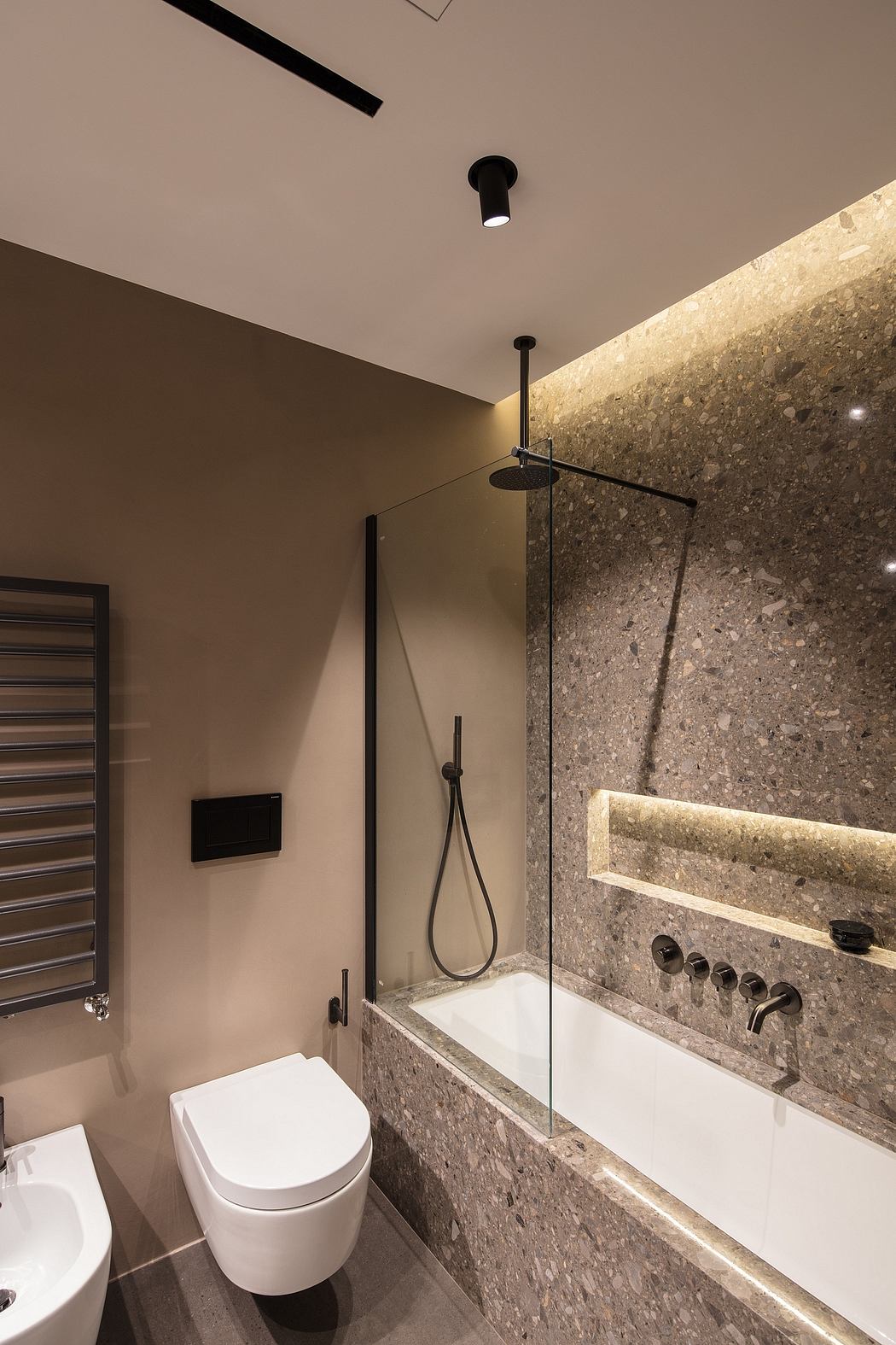 A contemporary bathroom with a stone-tiled wall, recessed lighting, and a minimalist shower.
