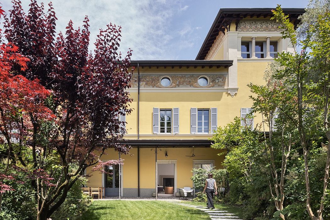 A charming yellow villa with intricate architectural details, surrounded by lush greenery.