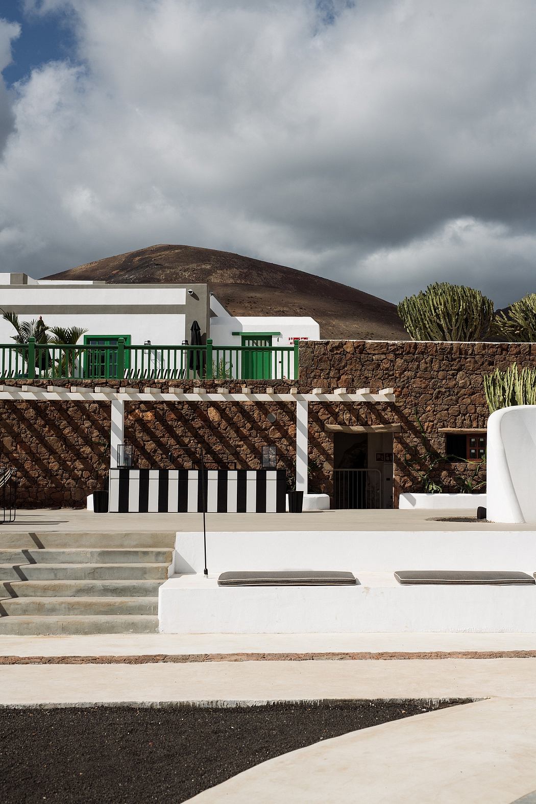 A modern architectural structure with bold contrasts of white, green, and stone elements.