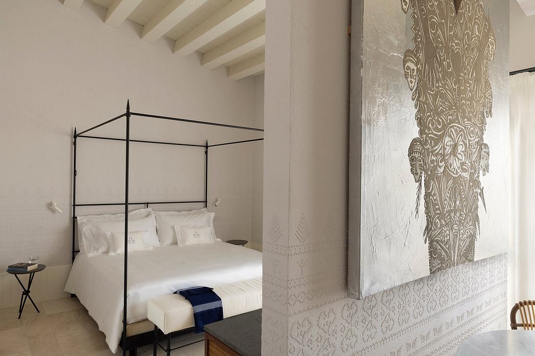 A serene bedroom with an ornate patterned wall, wood beams, and a canopy bed.