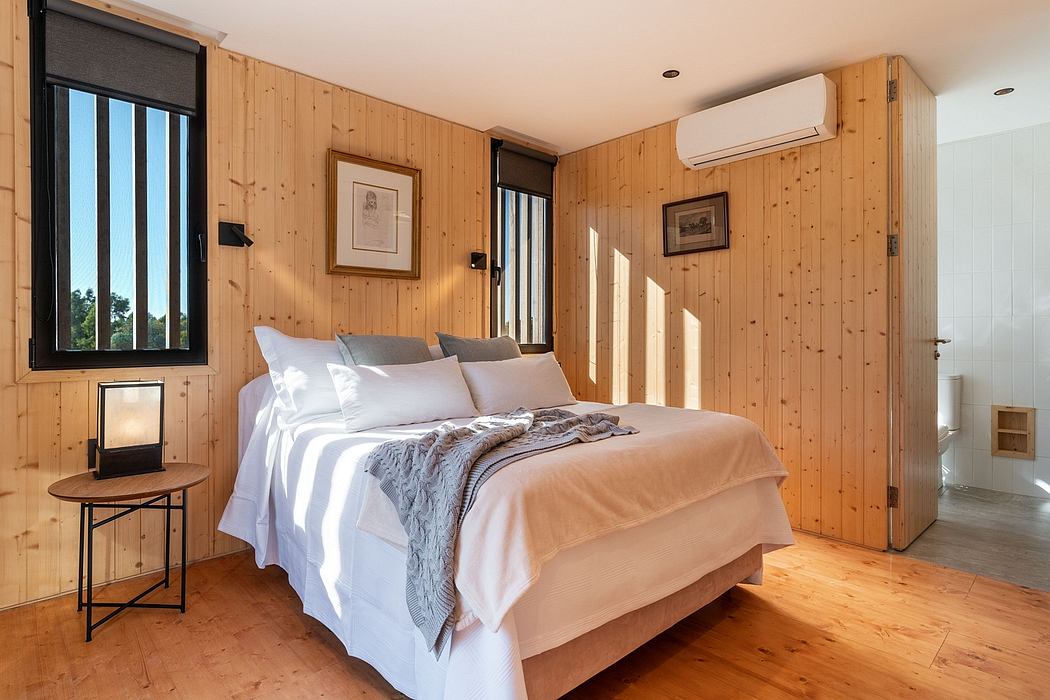 Cozy wooden bedroom with large window, plush bedding, and minimalist decor.