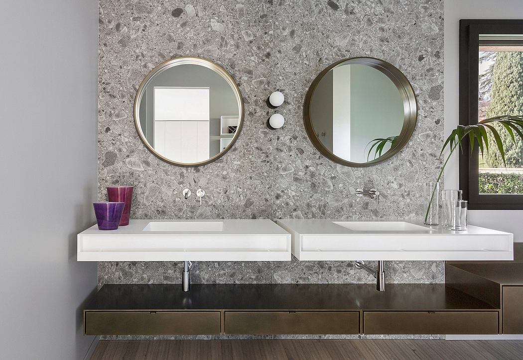 Modern bathroom with round mirrors, floating vanity, and terrazzo-patterned wall.