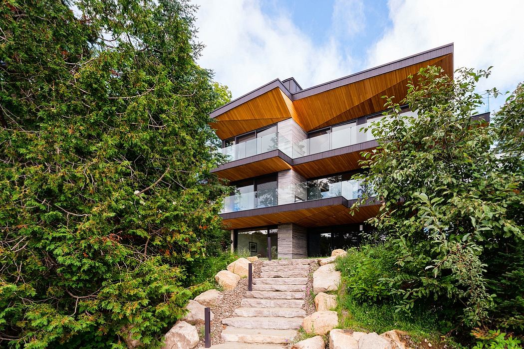 A modern, multi-story wooden structure with balconies and large windows amidst lush greenery.