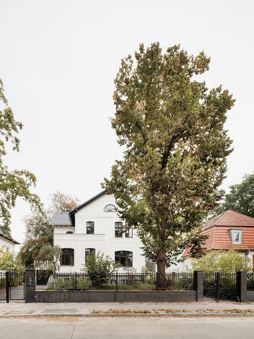 A majestic two-story home with intricate arched windows and a sprawling tree canopy.