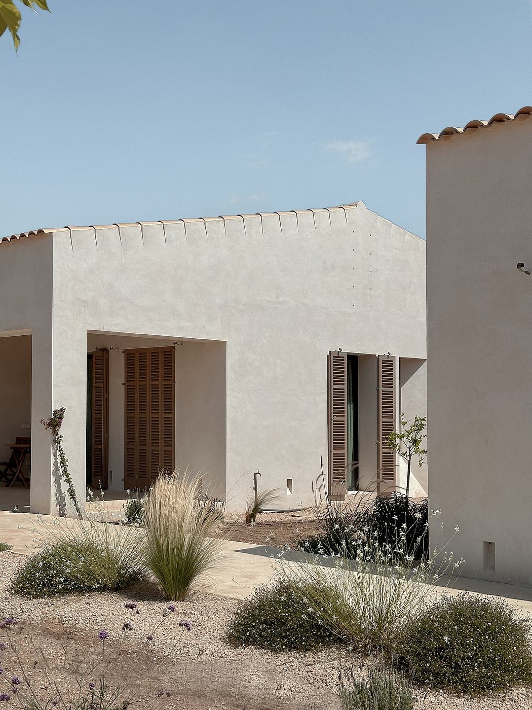 A Mediterranean-style architecture with a tiled roof, shuttered windows, and a desert-inspired landscape.